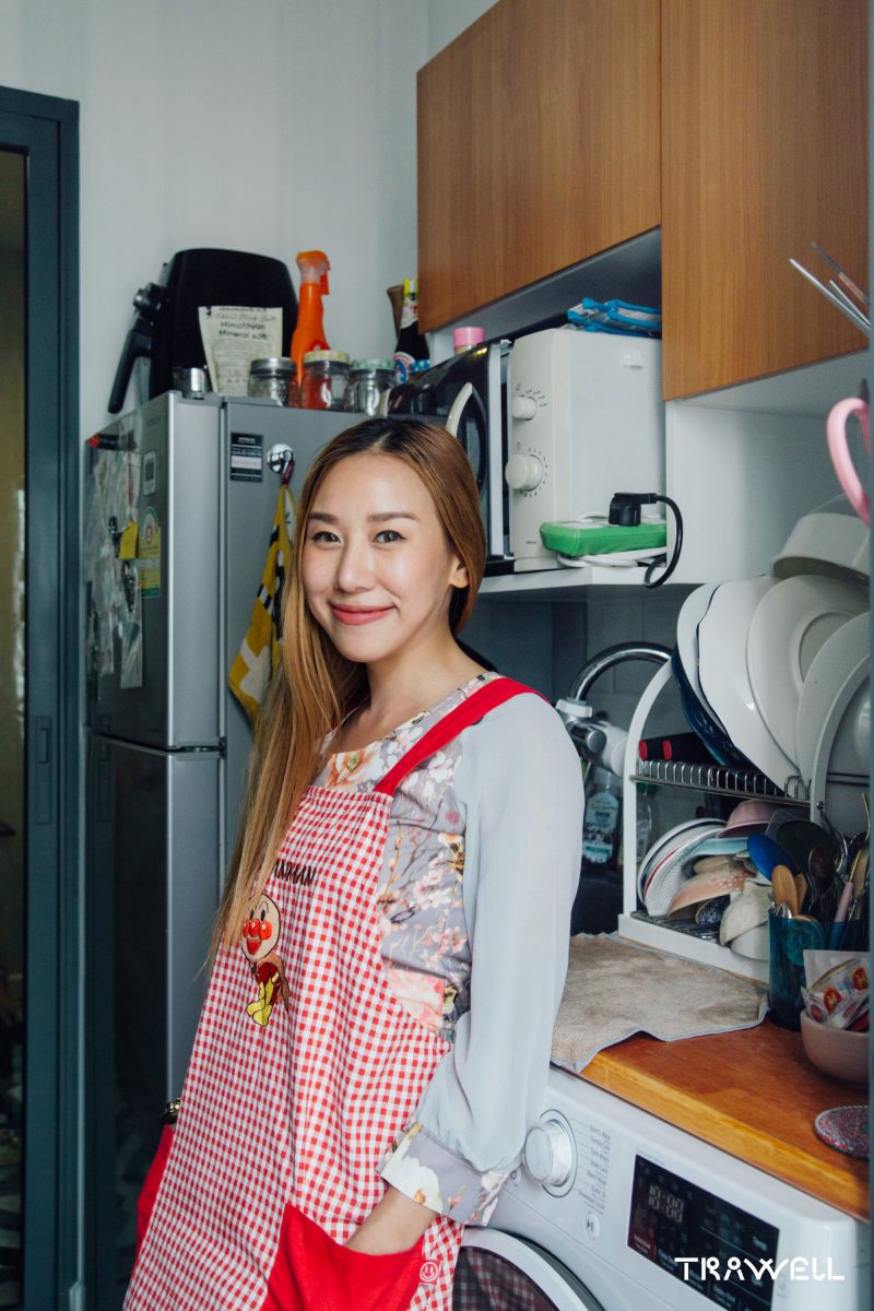 Young women in red apron smiling in her tiny kitchen